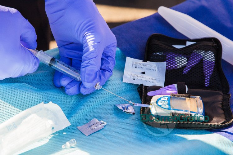 person using disposable syringe put specimen on blue and white glucose meter