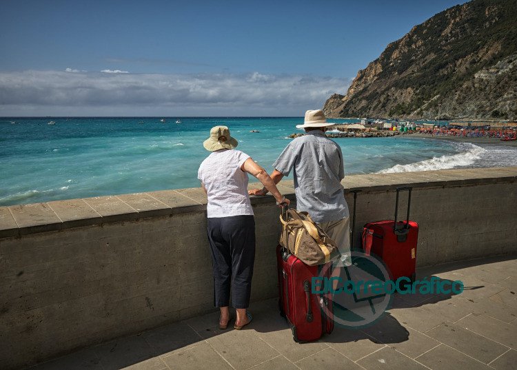 man and woman standing beside concrete seawall looking at beach