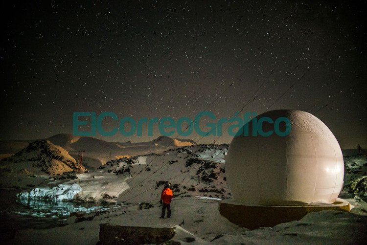 Estudiante de Ingeniería de la UNLP entre los guardianes de la Antártida Ezequiel Peschiera. A su derecha un domo que protege a las antenas de internet del viento y la nieve