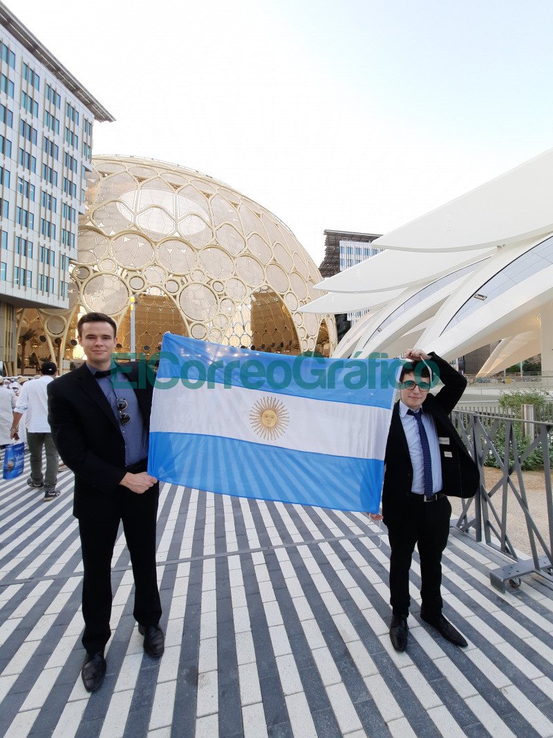 Con la bandera argentina Tomas Boschetto y Franco Ruffini. En el fondo un domo que es caracteristico de la Expo.